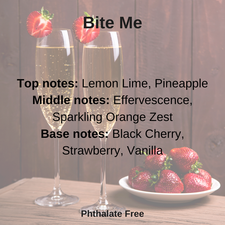 Bite Me is scent notes: a playful burst of fruity fun. Zesty lemon-lime and juicy pineapple create a bright, tangy start, followed by bubbly effervescence and sparkling orange zest. The finish is sweet with black cherry, strawberry, and a hint of creamy vanilla. Text is over 2 champagne filled flutes beside a plate of strawberries,