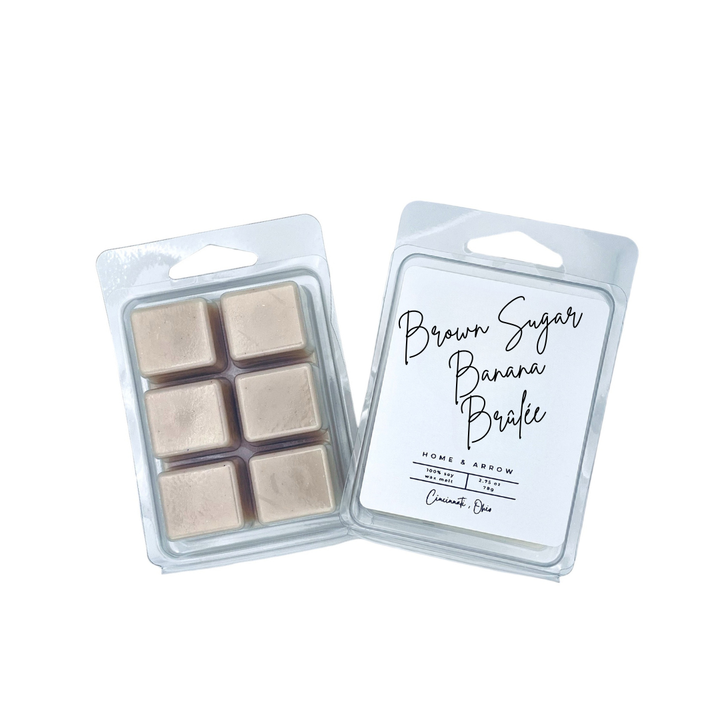 Two wax melts in clear plastic clamshell packaging on a white background. One package shows six beige wax cubes, and the other shows the front label reading 'Brown Sugar Banana Bark' with 'Home & Arrow' branding.