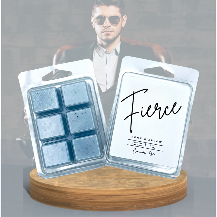  Fierce soy wax melts in a clamshell package dispayed on a wooden stand over a background of a well dressed man in sunglasses in a leather chair.