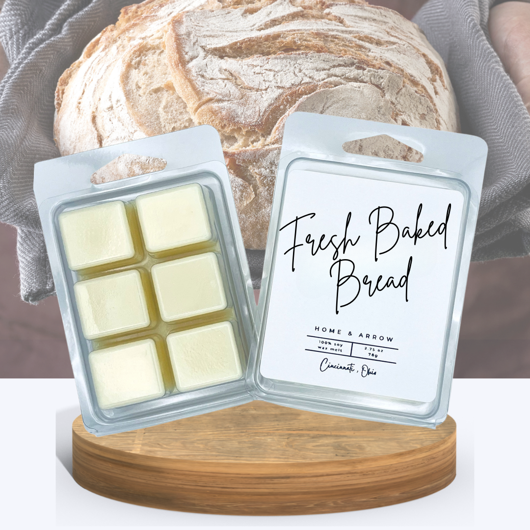 Fresh Baked Bread soy wax melts in a clamshell package dispayed on a wooden stand in front of a pretty artisan bread loaf.