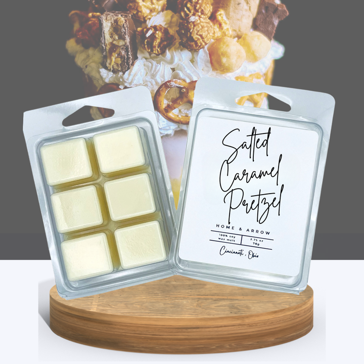 Salted Caramel Pretzel wax melts in clamshell packaging, displayed on a wooden stand with a caramel and pretzel dessert background.