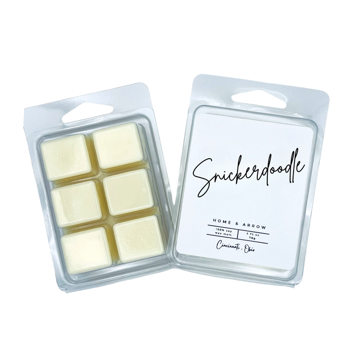 Two wax melts packages on a white background, one open showing six pale cream wax cubes and one closed with a white label reading Snickerdoodle and Home & Arrow.