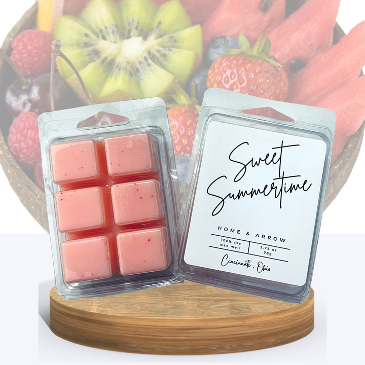 Sweet Summertime soy wax melts in clamsell packaging, displayed on a wooen stand with a  bowl of summer fruit in the background