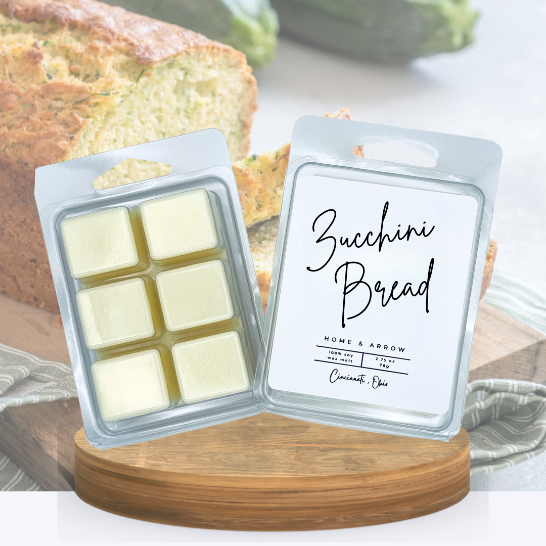 Zucchini Bread  soy wax melts in a clamshell package dispayed on a wooden stand in front of a cut loaf of yummy bread.